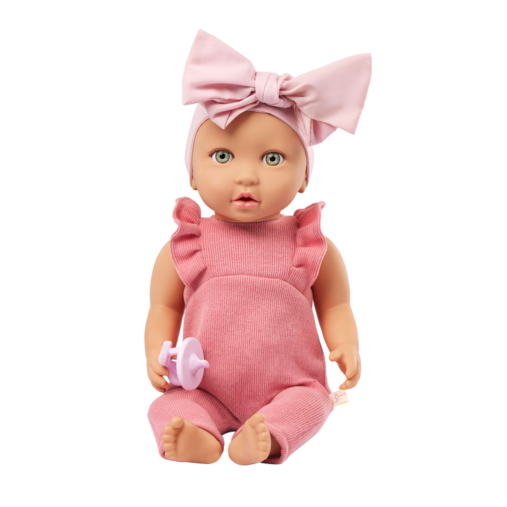 Baby doll in pink outfit with a large bow on a white background