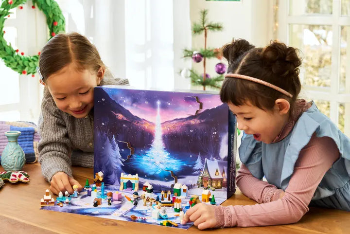 Two children playing with a Christmas-themed Advent calendar on a table.