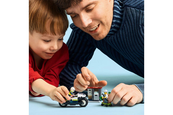 Man and child playing with toy cars on a light blue background