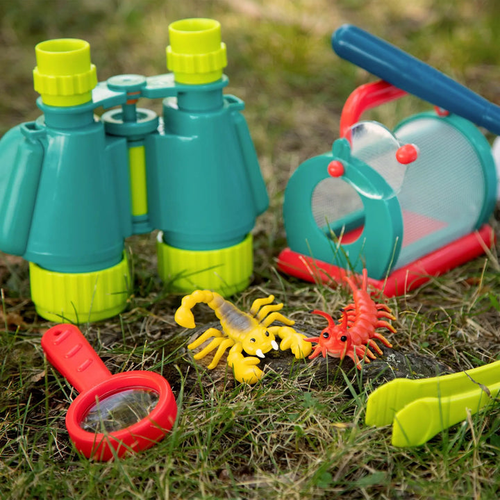 Children's outdoor exploration toys including binoculars, magnifying glass, and toy insects on grass and bug house