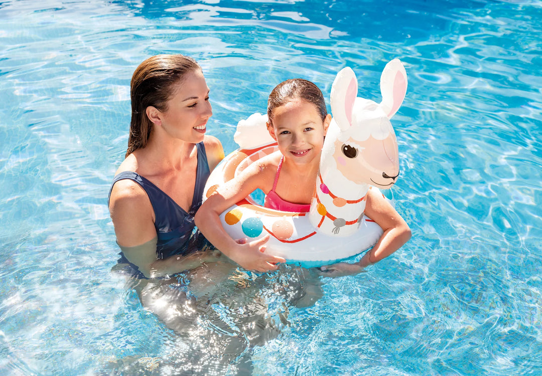 child using llama floatie in pool whilst lady stands next to her in pool and supports 