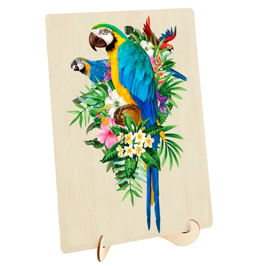 A rectangular wooden plaque or sign on a small wooden stand, featuring a colorful tropical illustration of two blue-and-yellow macaws among green leaves and pink and white flowers, shown against a plain white background.