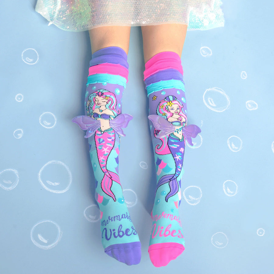 Colorful mermaid-themed socks with 'Mermaid Vibes' text on a light blue background.
