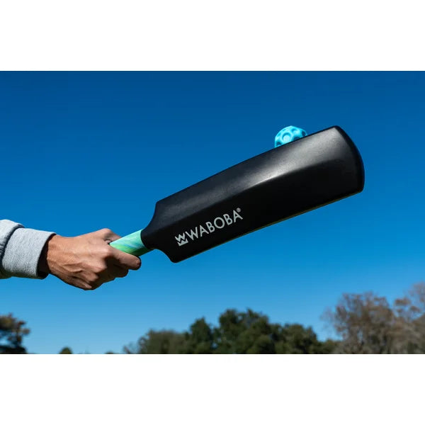 Person holding a Waboba ball and bat against a clear blue sky