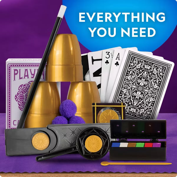 Magic show kit with gold cups, playing cards, a wand, purple pom-poms, a magic box, and a color palette on a purple background with a blue circle that reads 'EVERYTHING YOU NEED'.