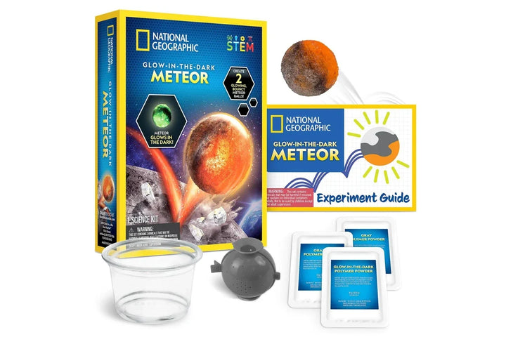 National Geographic STEM Glow in the Dark Meteor experiment kit with its box, experiment guide, clear cup, dark sphere, and tablets on a white background.