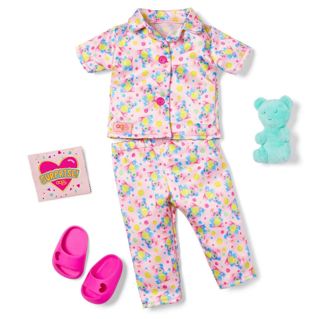 pajama outfit laid out on white background with pink teddy bear pajamas, teal teddy bear accessory, surprise bag, and pink slippers
