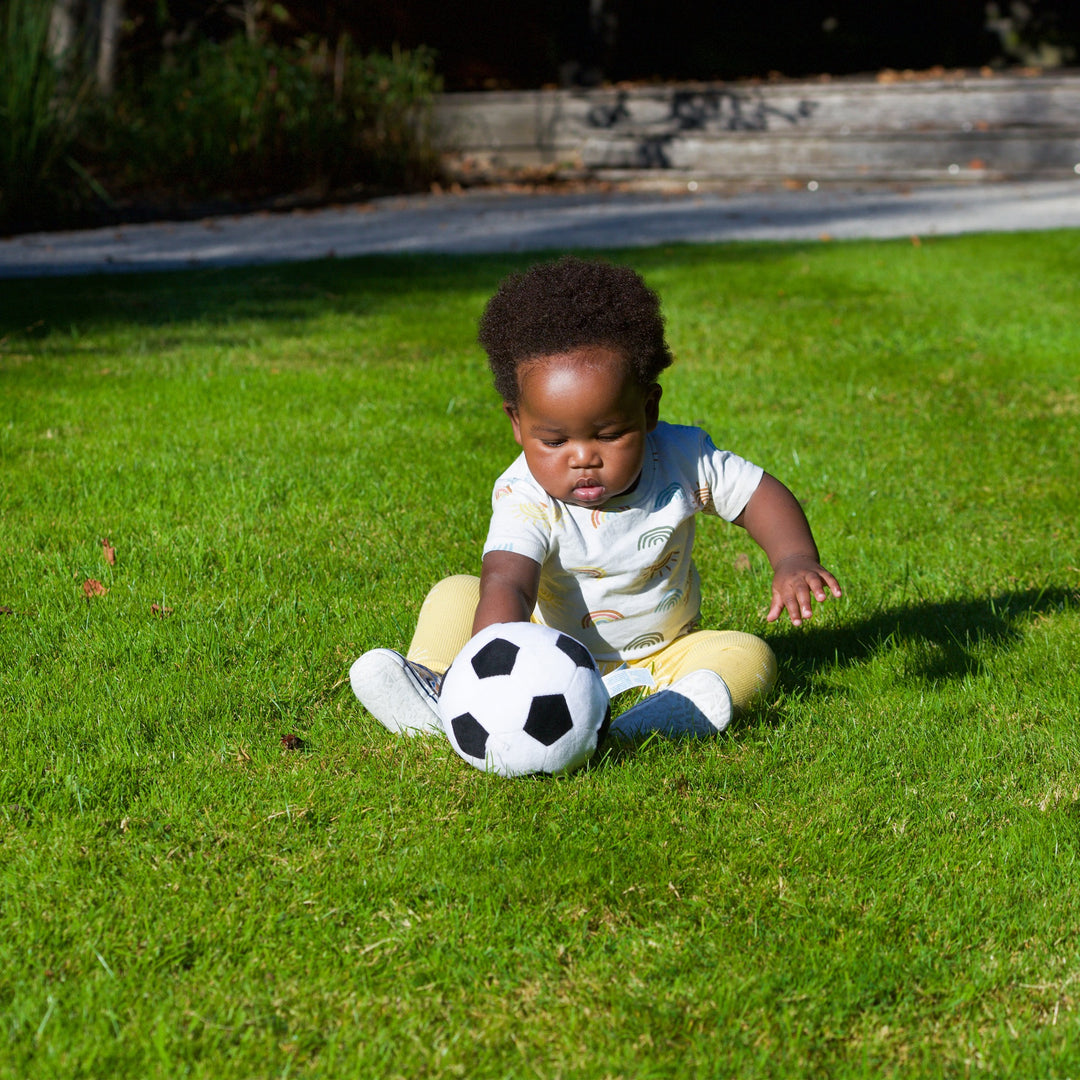 child on a patch of grass playing with playgro soccer ball