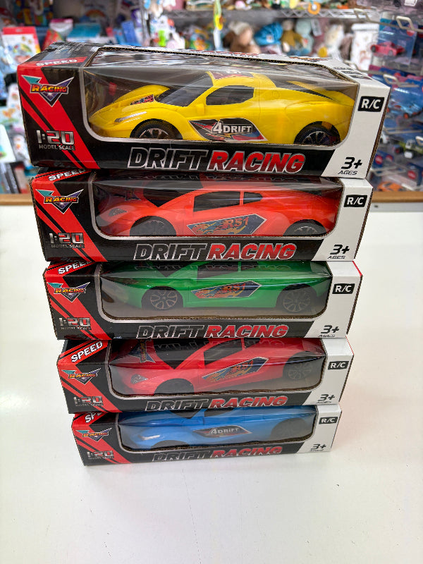 A stack of five boxed remote control drift racing cars in different colors: yellow, red, green, red, and blue, displayed on a white surface with a toy store background.