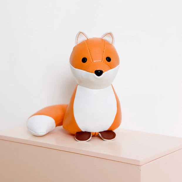Plush fox toy on a beige surface with a light gray background