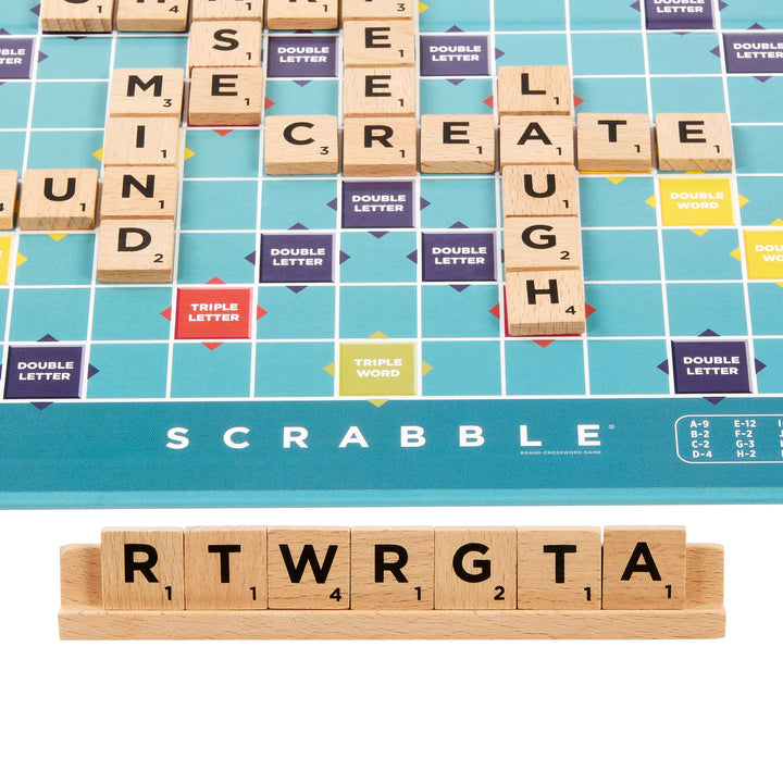 Scrabble game board with tiles spelling out 'CREATE LAUGH' and a set of tiles on top.