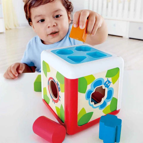 Child playing with a colorful shape sorting cube toy.