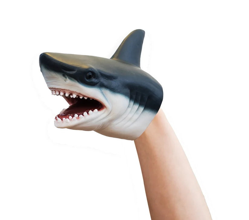 A shark-shaped hand puppet worn on a person's hand, with an open mouth showing teeth and a dark gray and white body, isolated on a white background.