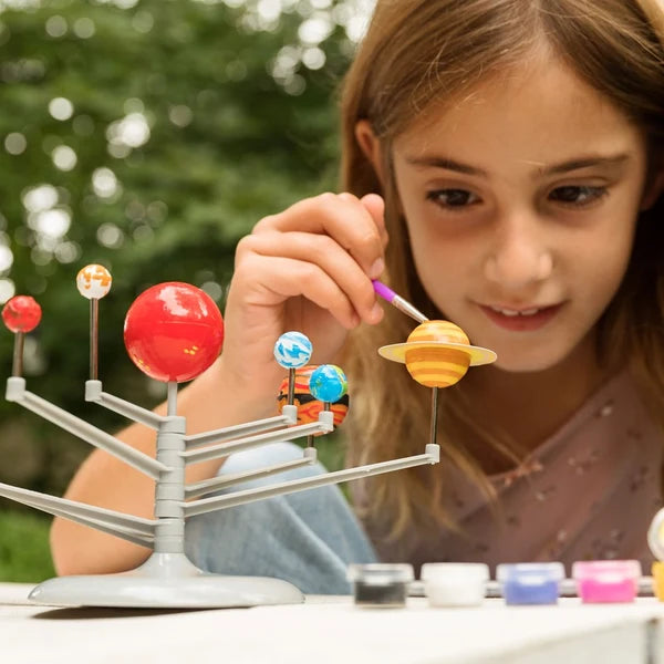 Girl playing with a solar system model outdoors