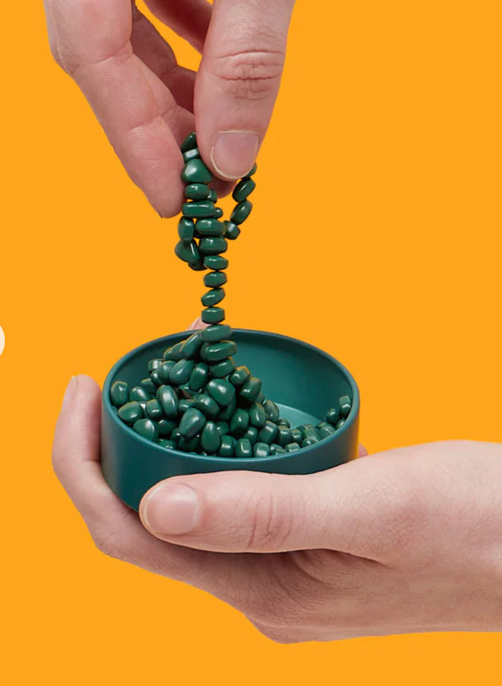 Green spiral puzzle toy being held by a hand against an orange background