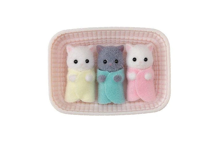 Three small Sylvanian Families Persian cat triplets, one pink, one gray, and one yellow, in a checkered container on a white background.