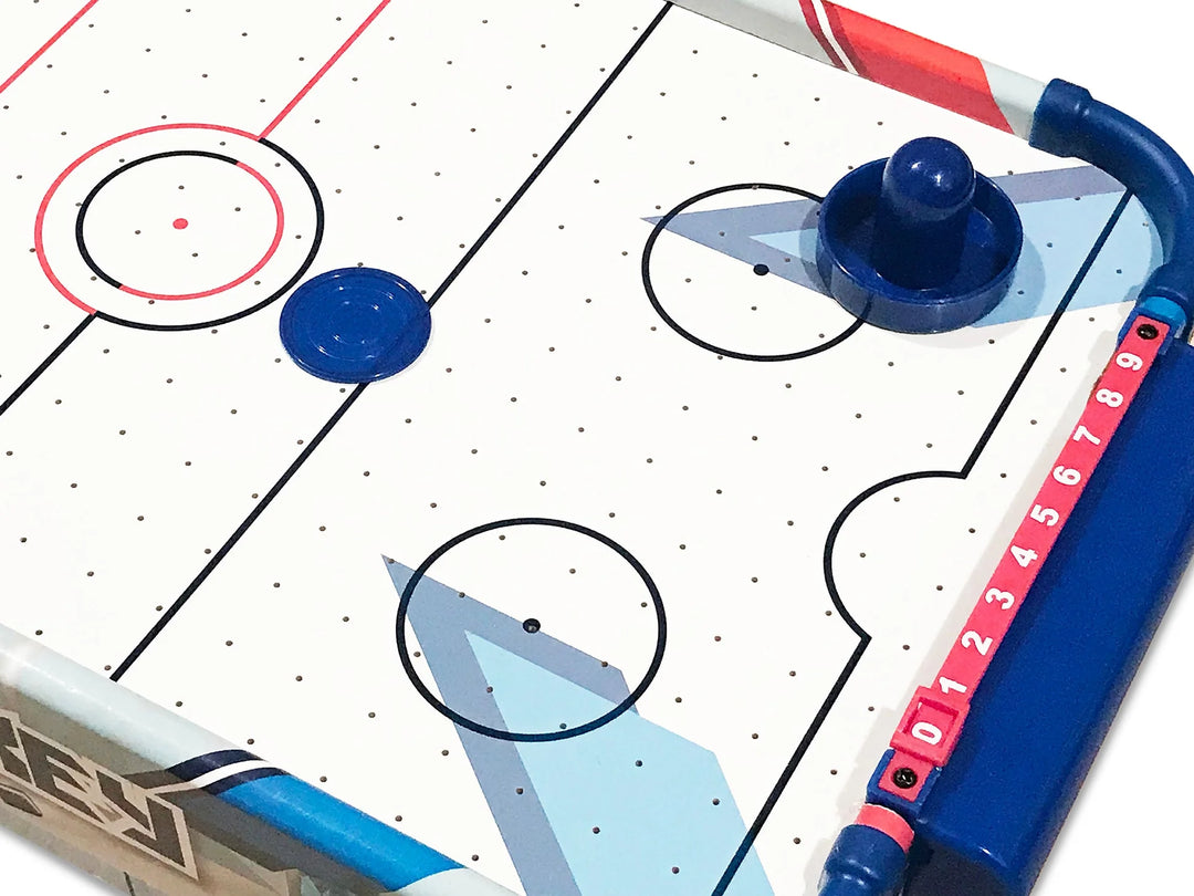 Close-up of a hockey game setup with sticks and puck on a grid-patterned surface.