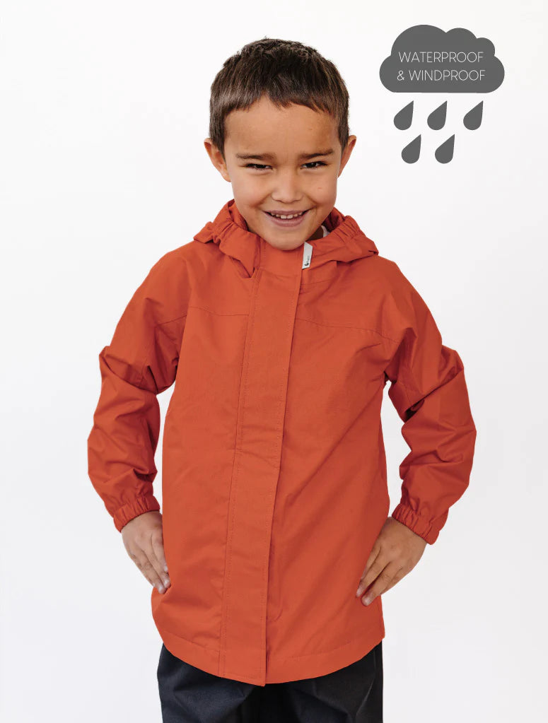 Child wearing an orange waterproof jacket on a white background