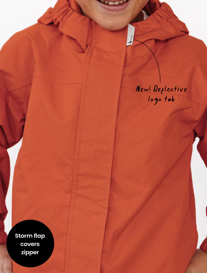 therm burnt Orange raincoat with reflective logo tab and storm flap feature on a white background