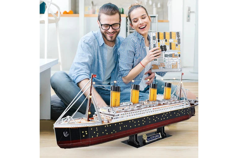 Two people with a large titanic cubic fun model ship indoors