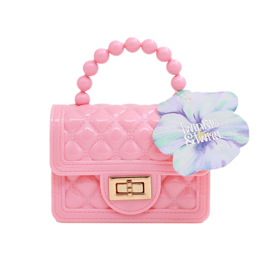 Pink quilted handbag with beaded handle and flower accessory on a white background