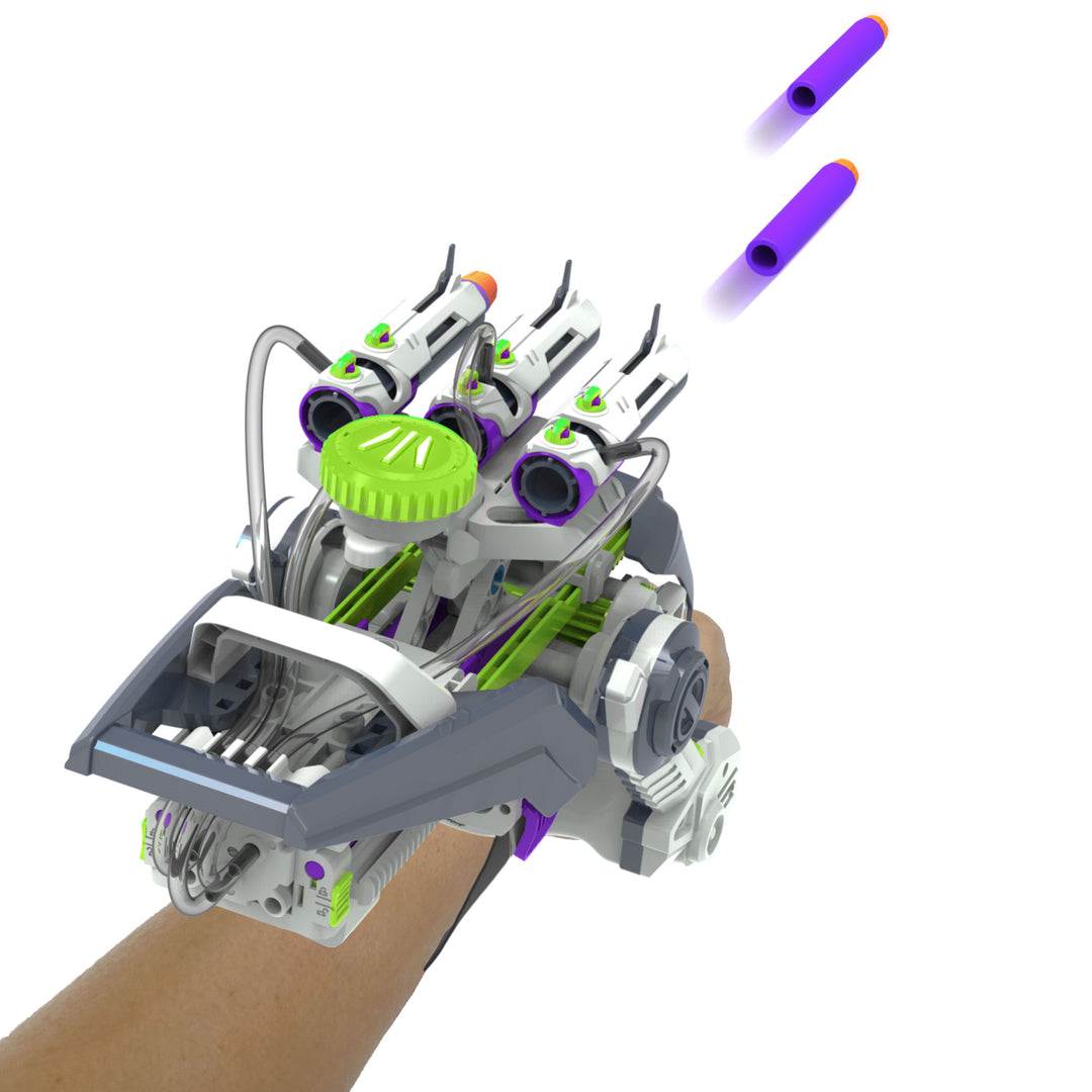 A futuristic robotic arm or prosthetic device worn on a person's forearm, shown against a plain white background with two purple toy dart-like accessories floating above. The device is primarily gray and white with bright green accents and black details.