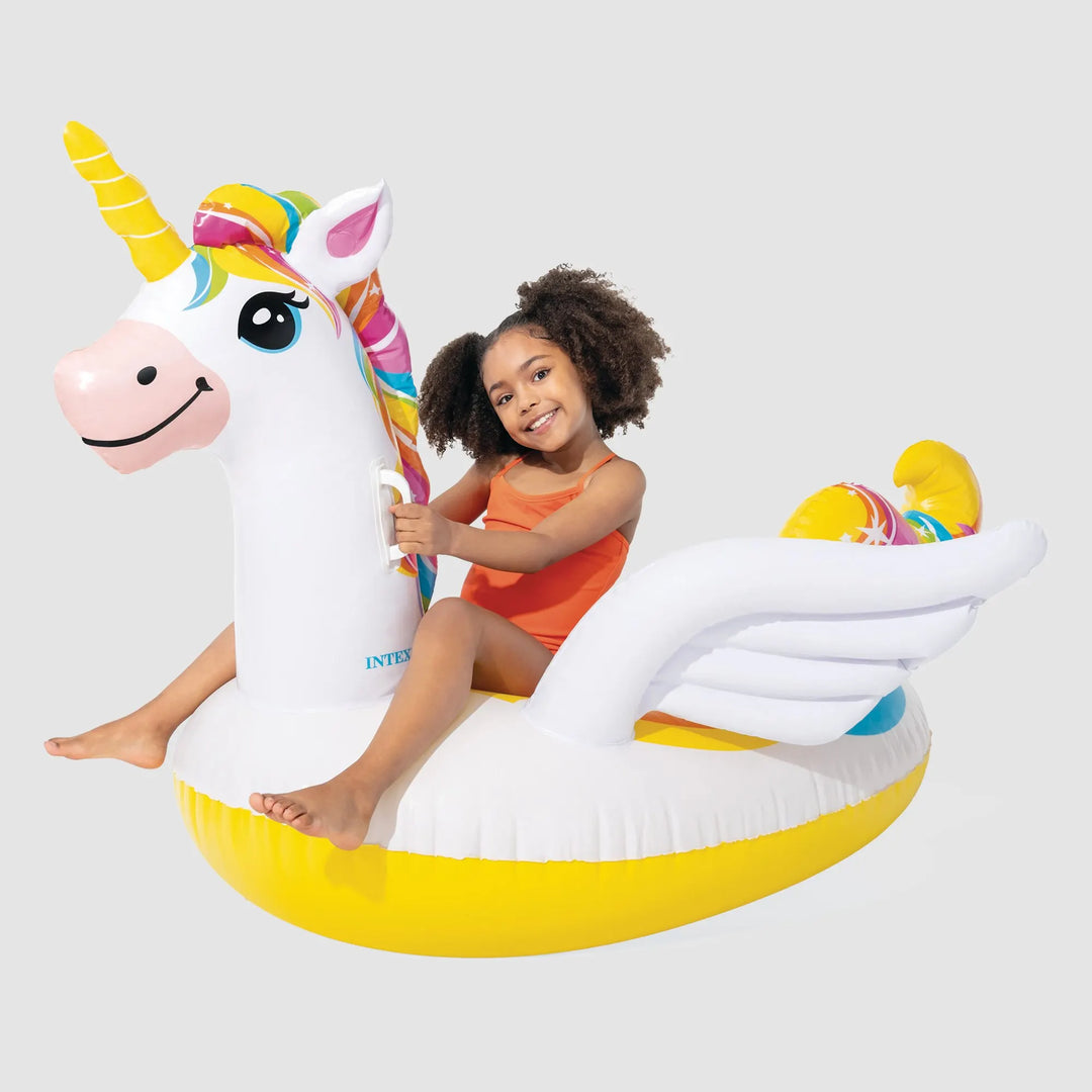 girl sitting on unicorn ride on pool float on a  grey background