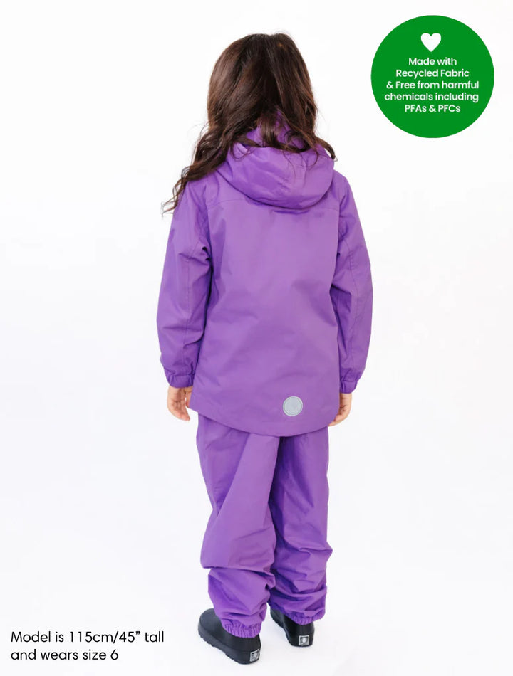 Child wearing a purple snowsuit with a green label indicating recycled fabric.